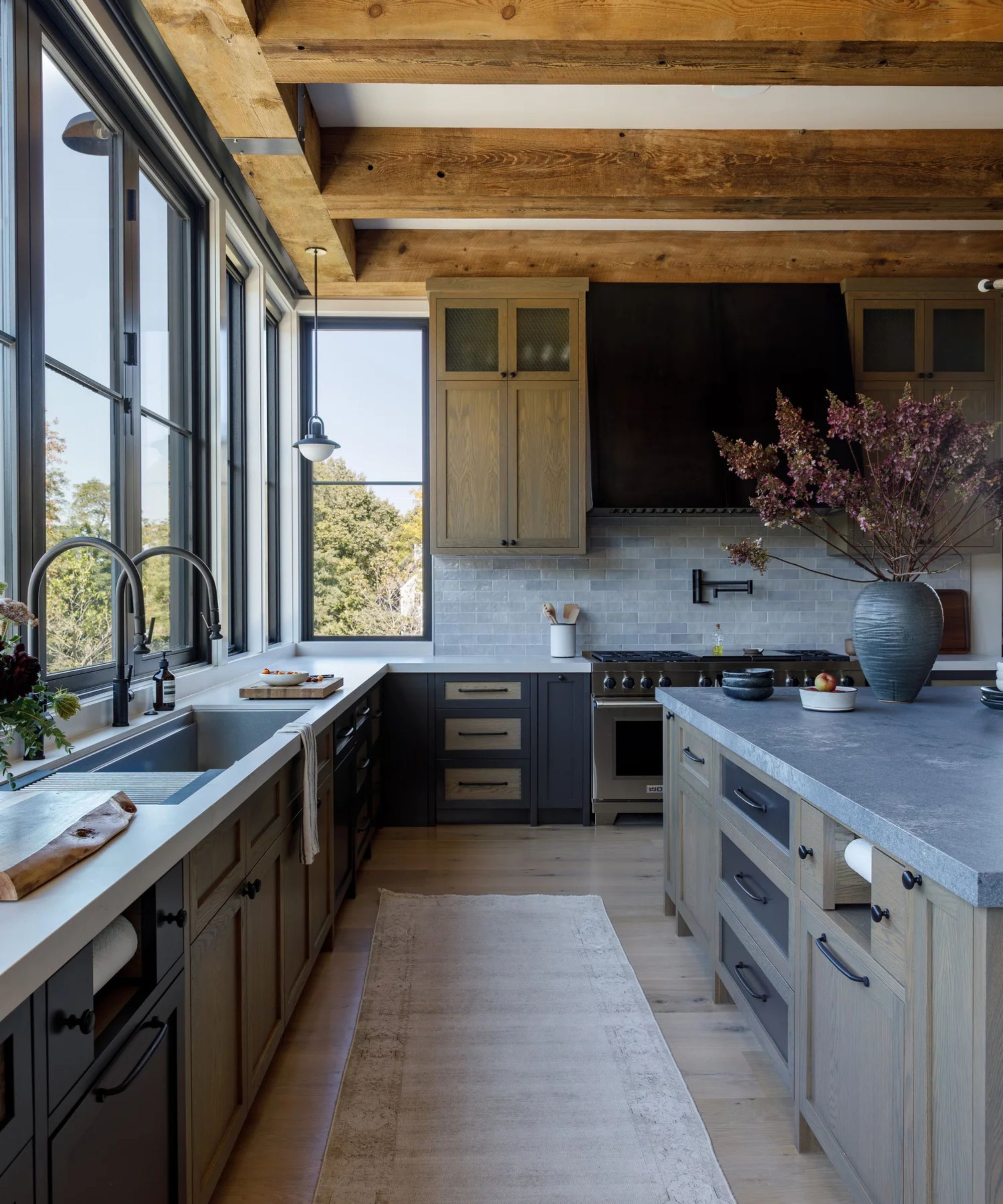 A rustic kitchen with a mix of dark blue and natural oak cabinets