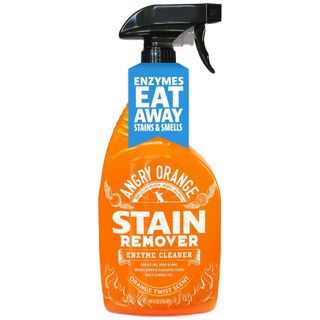 A side on view of an orange spray bottle of enzyme cleaner with a black spray lid and blue label