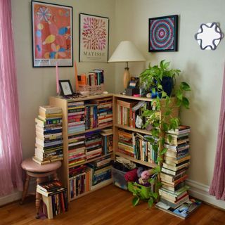 A small living room bookshelf with stacks of books around it