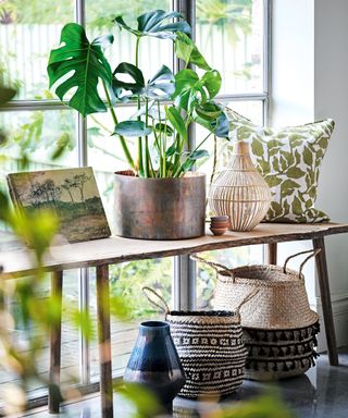 Fall planter ideas with monstera house plant inside copper planter with natural woven baskets on wooden table