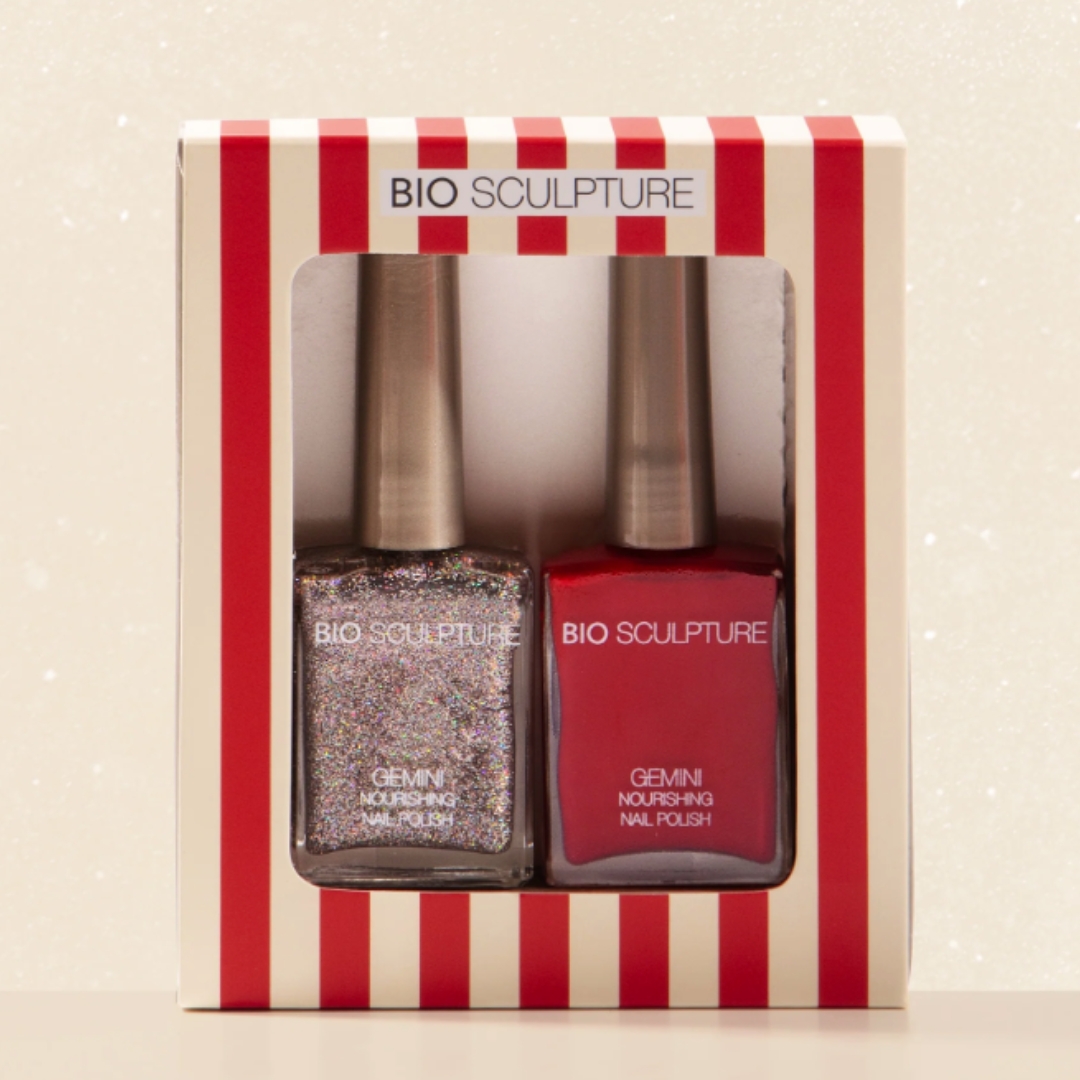 A product shot of the Bio Sculpture Showstopper - Christmas Polish Gift Set, which features a classic red nail polish and a silver glitter polish, on a cream glitter background