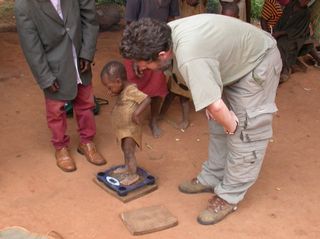 Scientist Fernando Ramirez Rozzi uses an electronic scale to measure the weight of a Baka child.