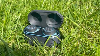 Bang & Olufsen Beoplay E8 Sport earbuds in the charging case on some grass
