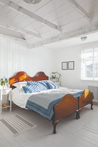 A white washed bedroom with a white wood panelled ceiling