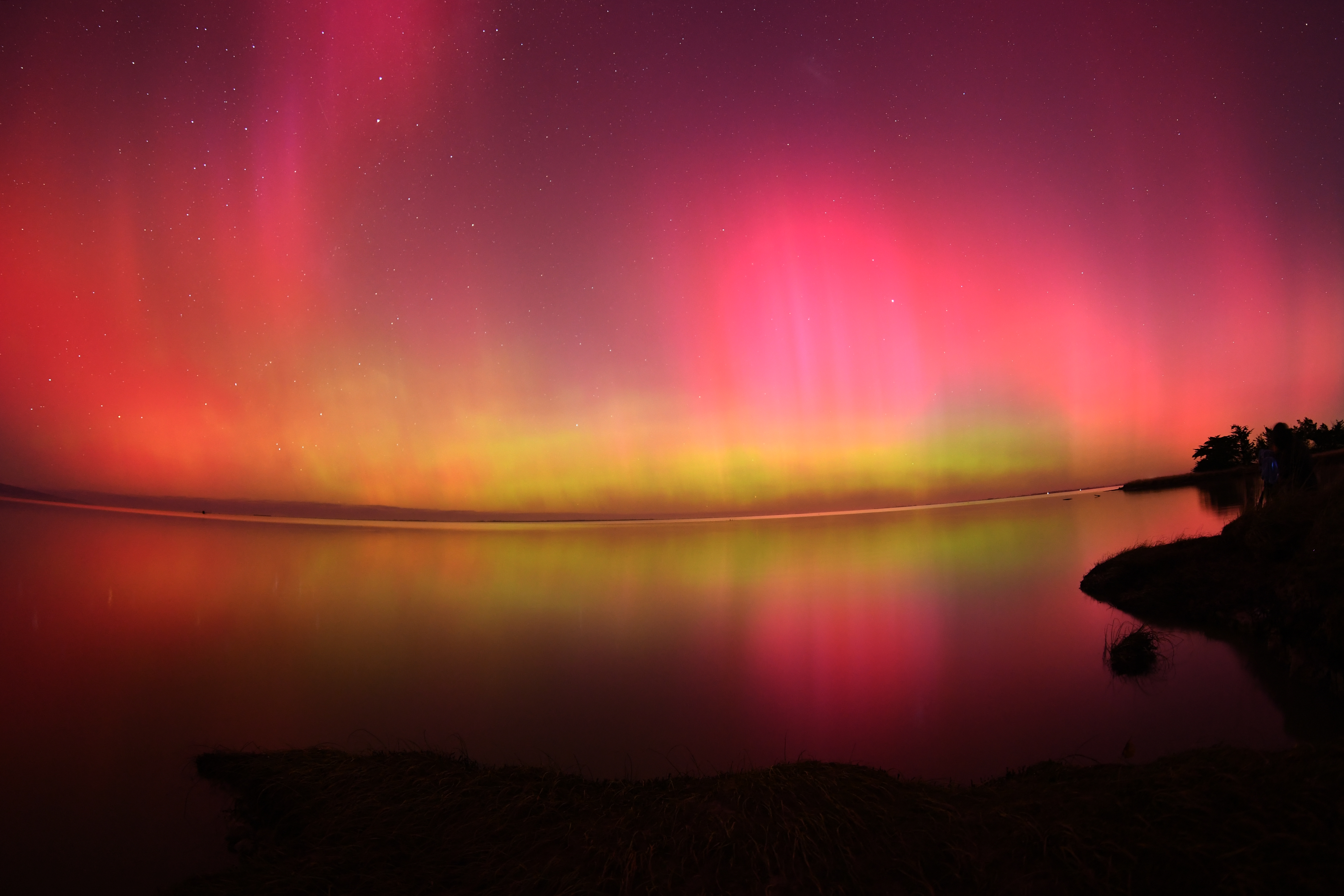 The Aurora Australis, also known as the Southern Lights, glow on the horizon over waters of Lake Ellesmere on the outskirts of Christchurch on May 11, 2024. The most powerful solar storm in more than two decades struck Earth, triggering spectacular celestial light shows from Tasmania to Britain -- and threatening possible disruptions to satellites and power grids as it persists into the weekend.