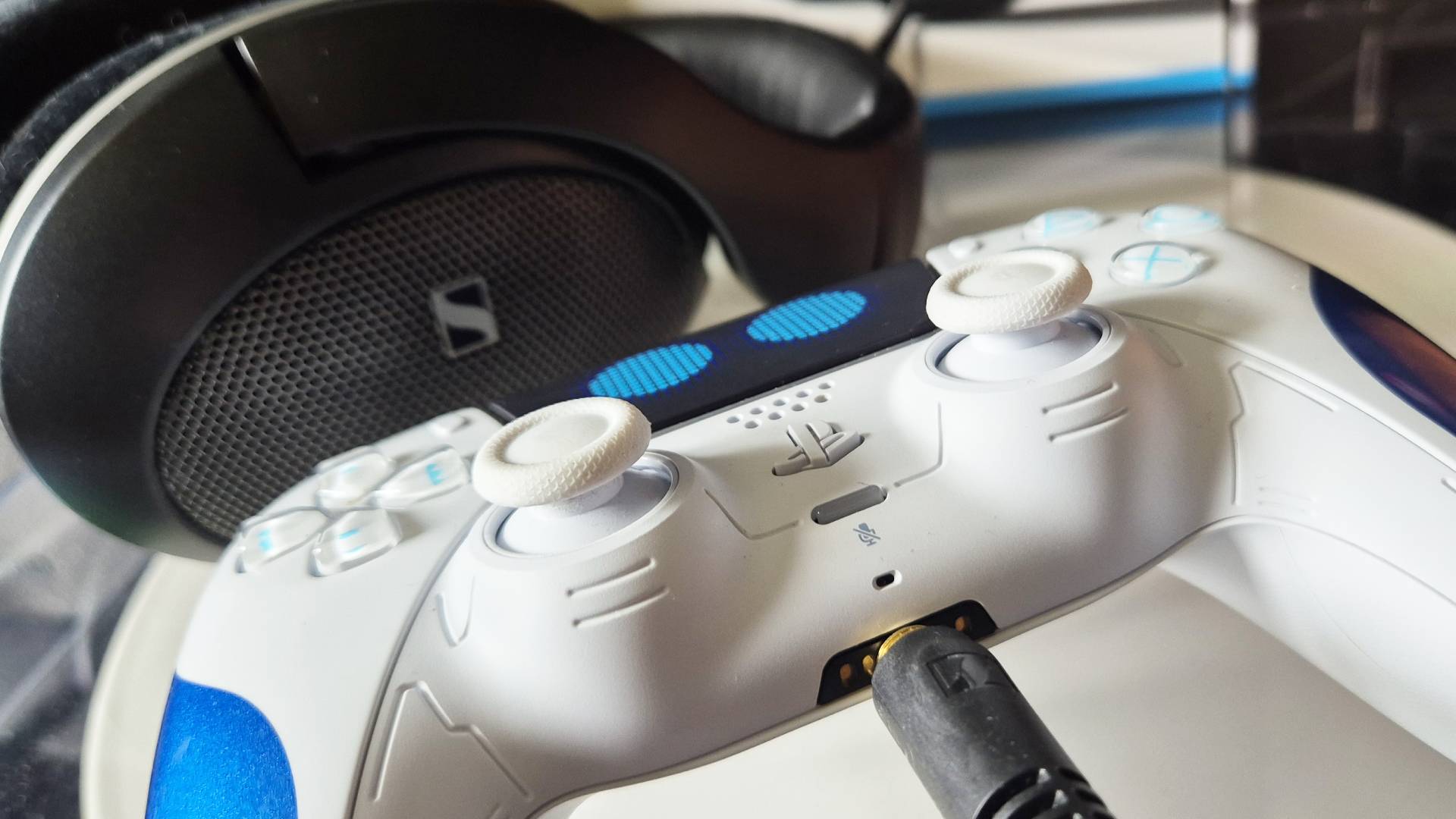 Close up of the official Astro Bot DualSense PS5 controller, with the Sennheiser HD 550 headphones plugged into them, taken by Rosalie Newcombe.
