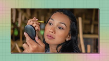 young woman applying eyeliner in compact mirror