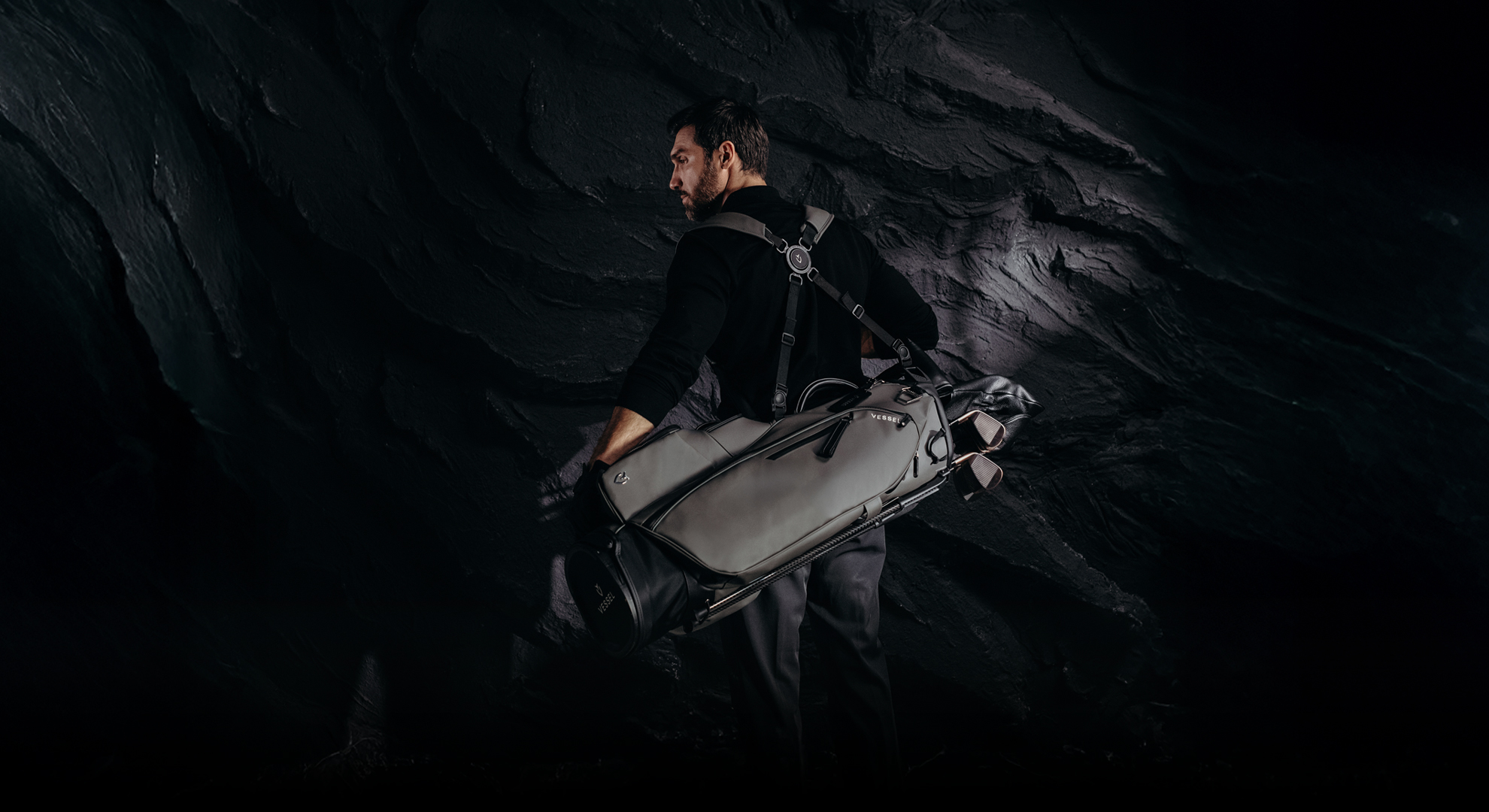 A man carrying a black Vessel stand bag indoors