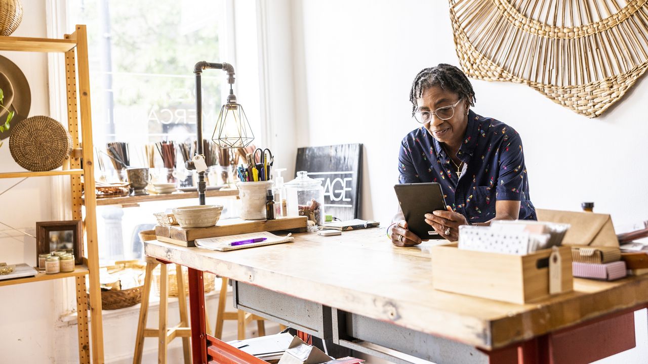 A small business owner in her store looks at a tablet.