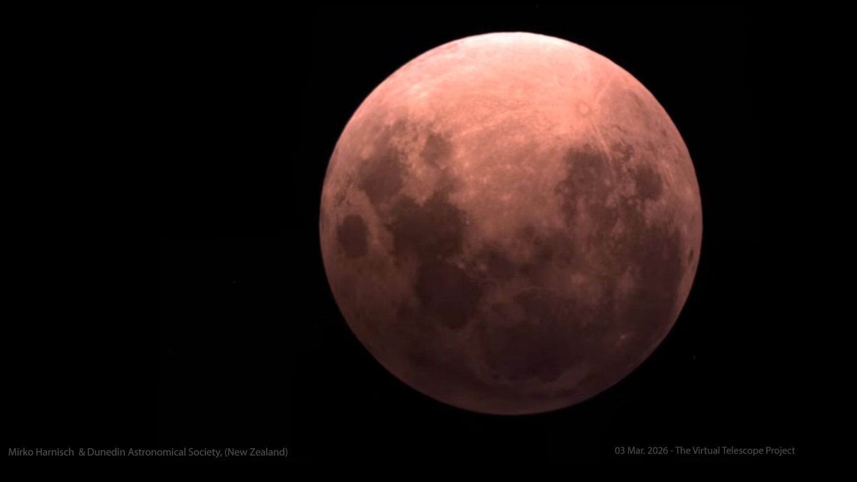 A red full moon appears against a black sky during a total lunar eclipse.