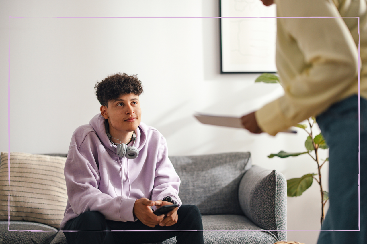 Teenage Boy Sitting on the Sofa and Listening to Someone Talking To Him