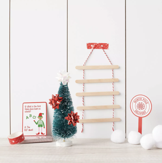 an elf kit featuring a mini Christmas tree, a ladder, a north Pole sign and a joke card