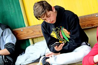 A teenage boy looking down at his smartphone.