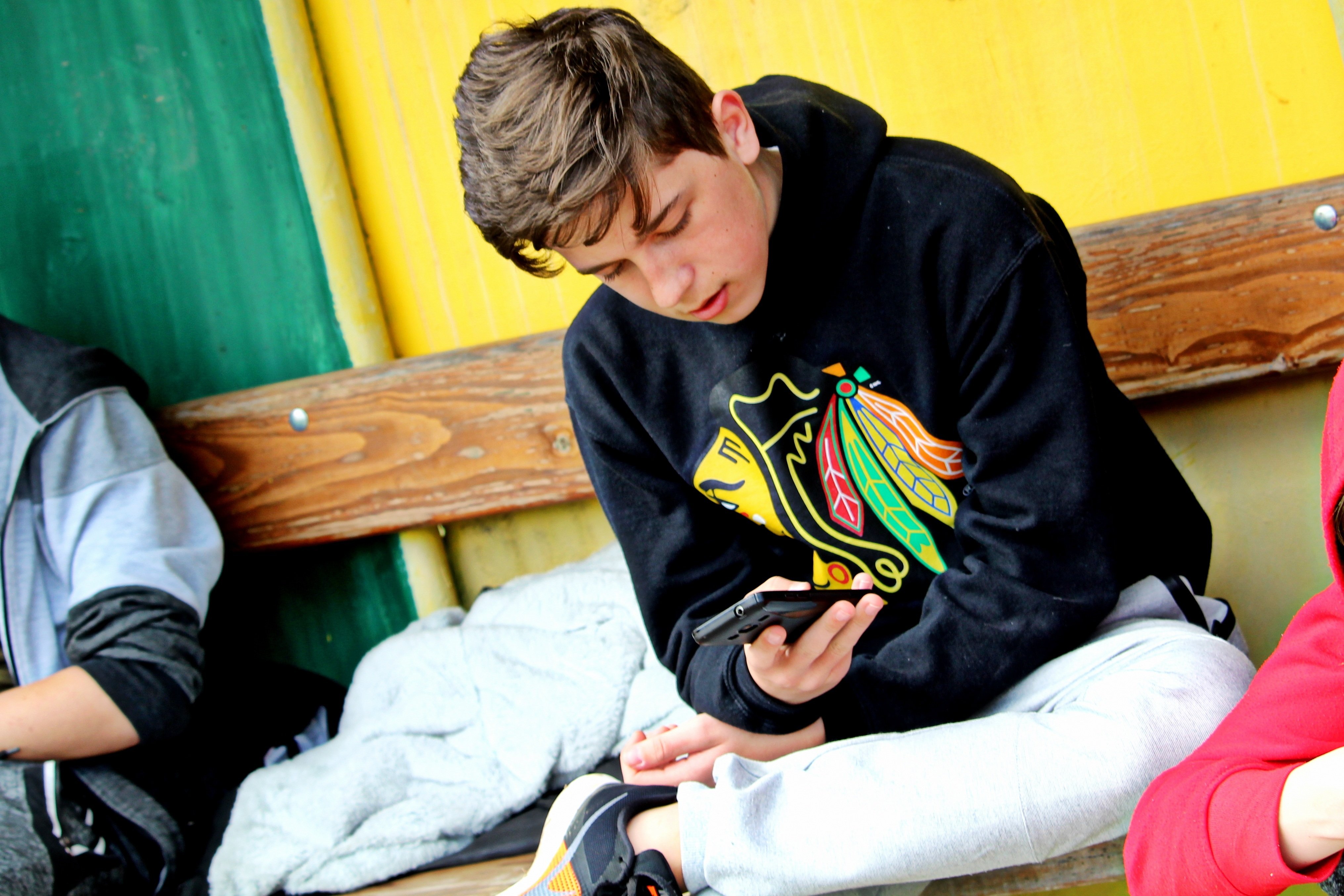 A teenage boy looking down at his smartphone.