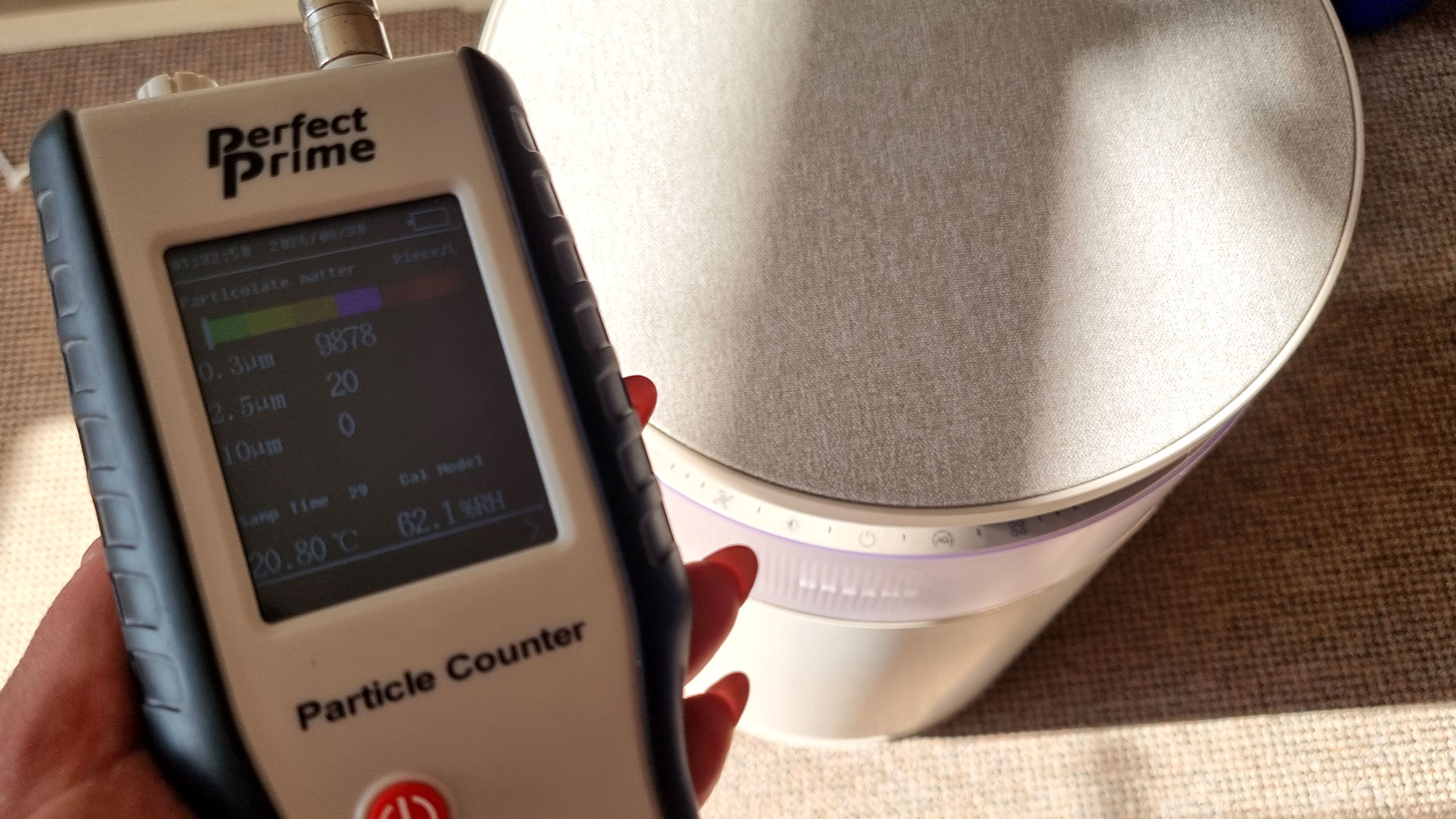 a close-up picture of our reviewer testing the Dreame FP10 air purifier using a Perfect Prime air particle monitor