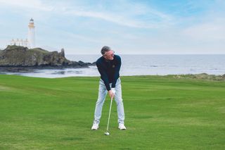 Steve North preparing to hit an iron shot in the first cut of rough on the 10th hole, in front of the famous lighthouse at Trump Turnberry