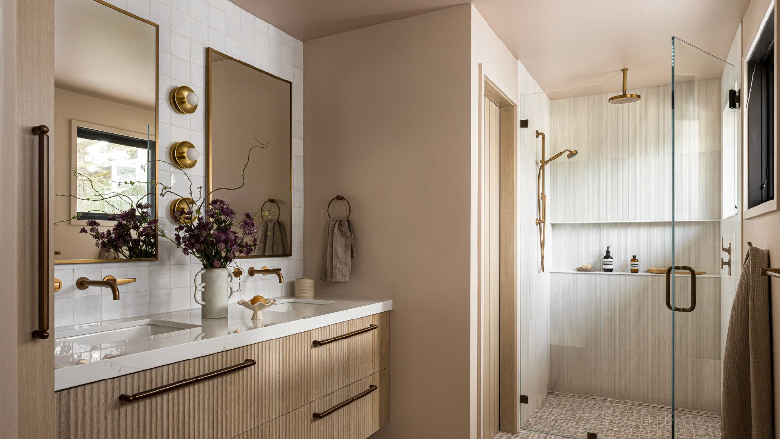 A wood bathroom with white wall tiles and two rectangular mirrors above the double vanity