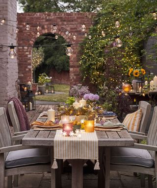 An outdoor table set in the evening with lights