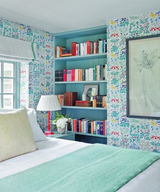 bedroom with colorful patterned wallpaper, aqua bookcase, bed with green throw