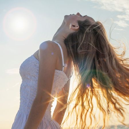 a woman playing with her hair in the sun - summer hair care