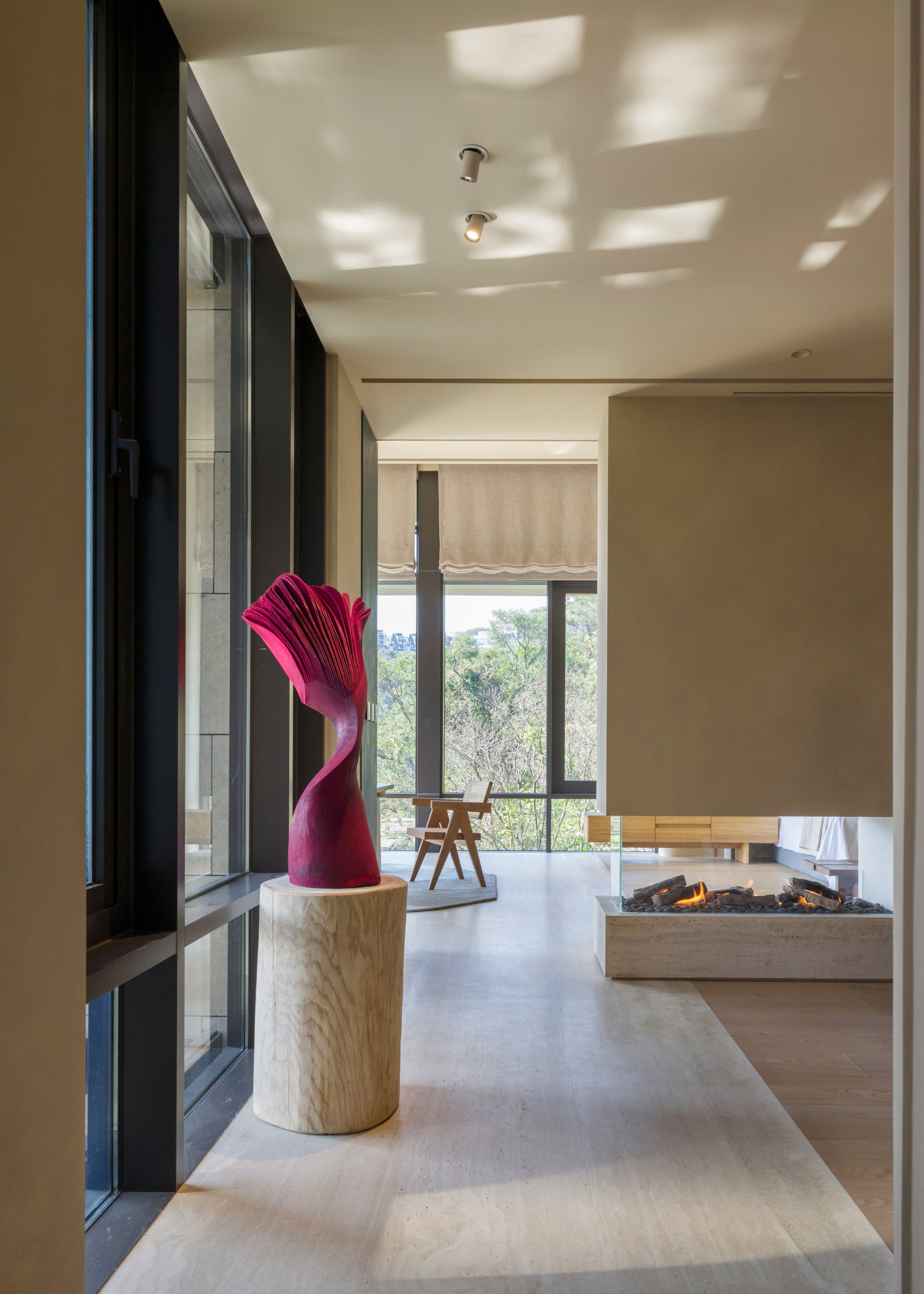 A bright, airy living room with a floating fireplace and a plinth with a pink structural statue