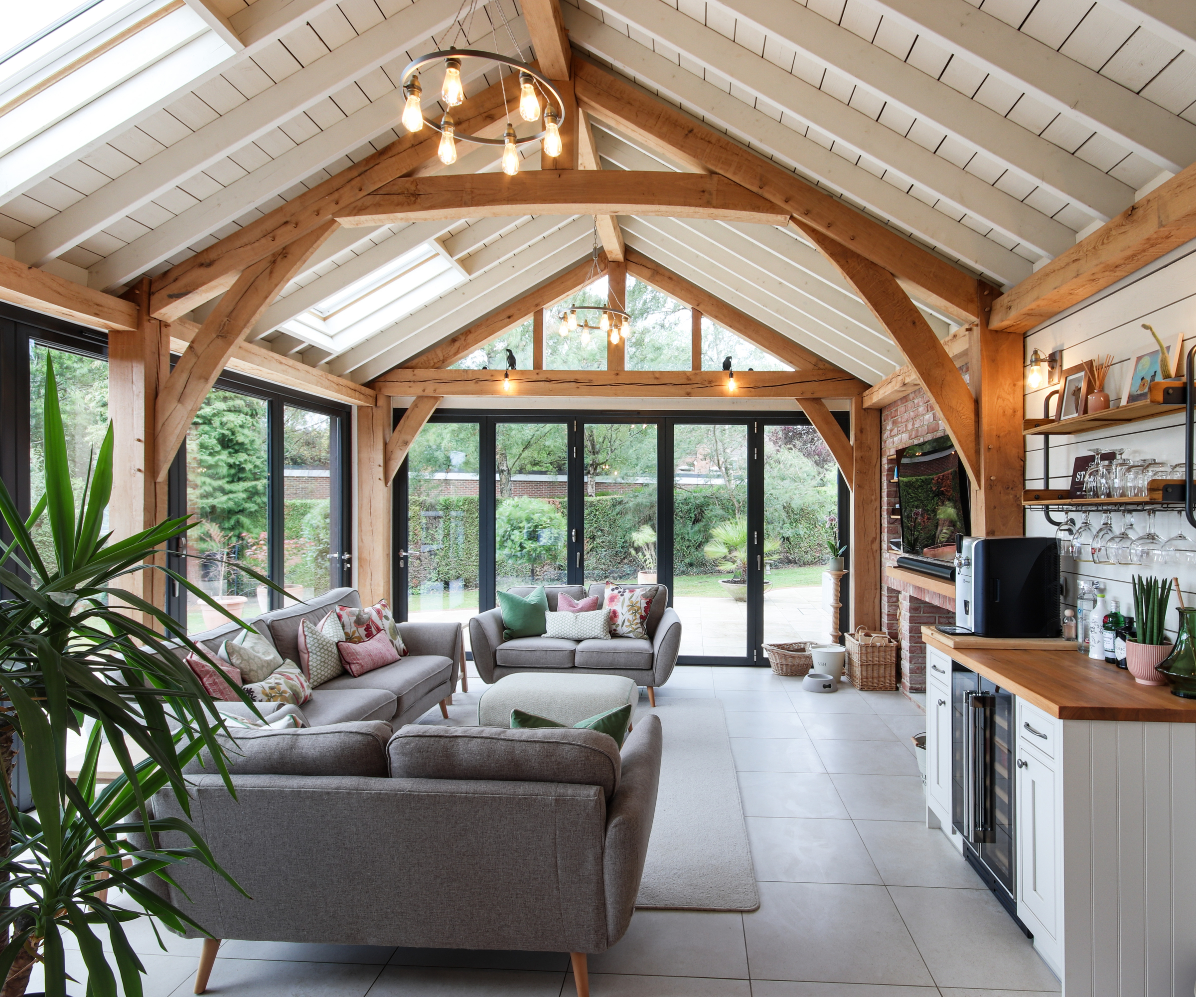 inside of timber frame extension in living room area with white timber clad ceiling and exposed oak beams and trusses