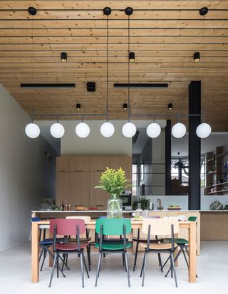 an industrial style wooden kitchen with a dining table and multi-coloured chairs. Veerusha Diah and Yogesh Bhola's extended Woodford Green home is an uber-stylish space to hang out