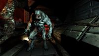 Still from the video game Doom 3. A giant, muscular, grotesque demon coming down a dark corridor.