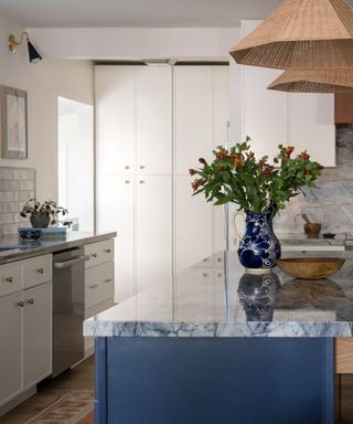 white kitchen with pantry doors and a navy kitchen blue marble countertops and vintage accessories