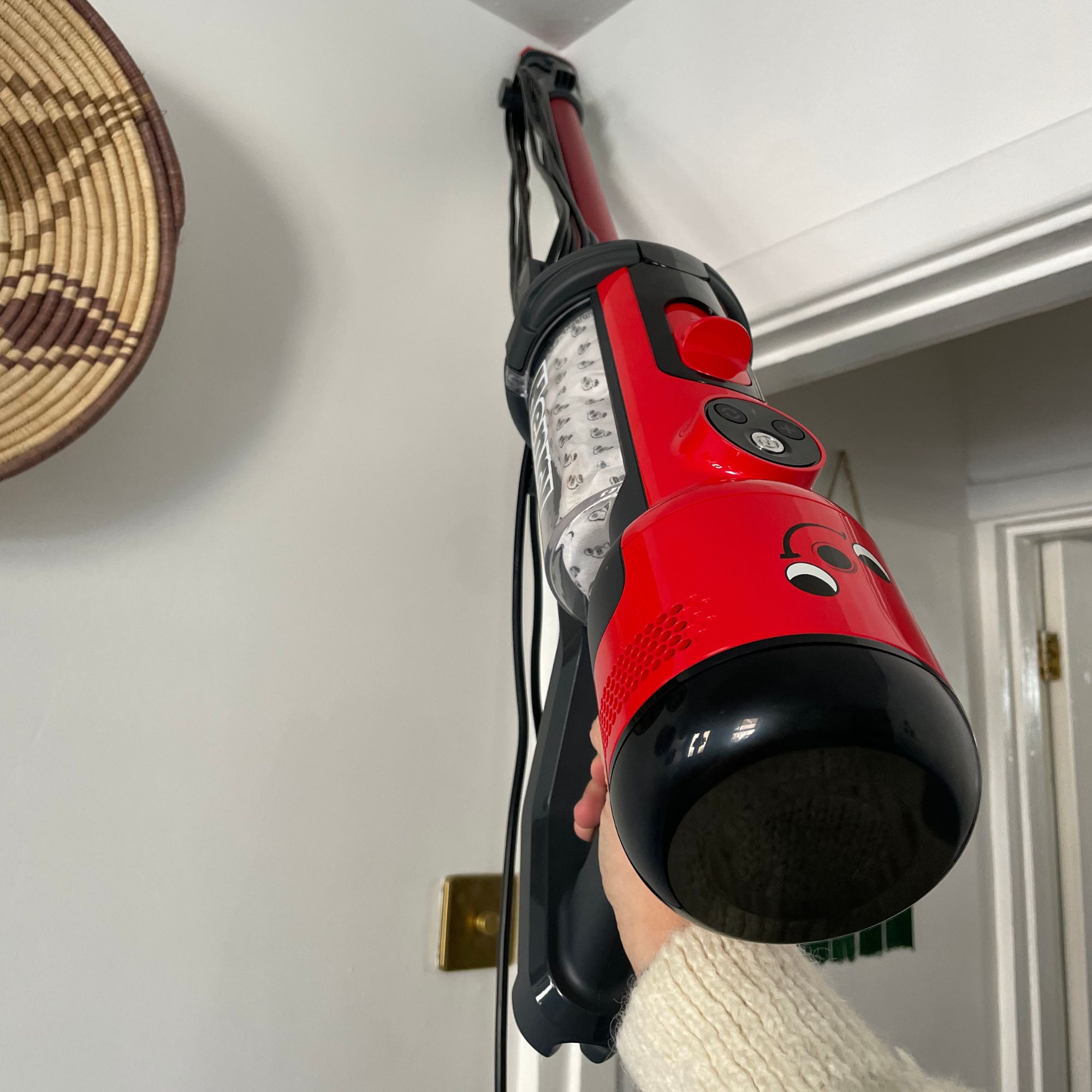 Using the Henry Quick Corded Vacuum Cleaner to clean cobwebs from the corner of a white room