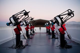The MEarth-South telescope array, located on Cerro Tololo in Chile, searches for planets by monitoring the brightness of nearby small stars. This photograph shows the array, comprising eight 40cm telescopes, at twilight.