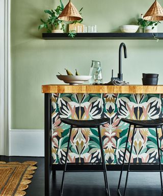 Kitchen island covered in patterned wallpaper with black accessories in room