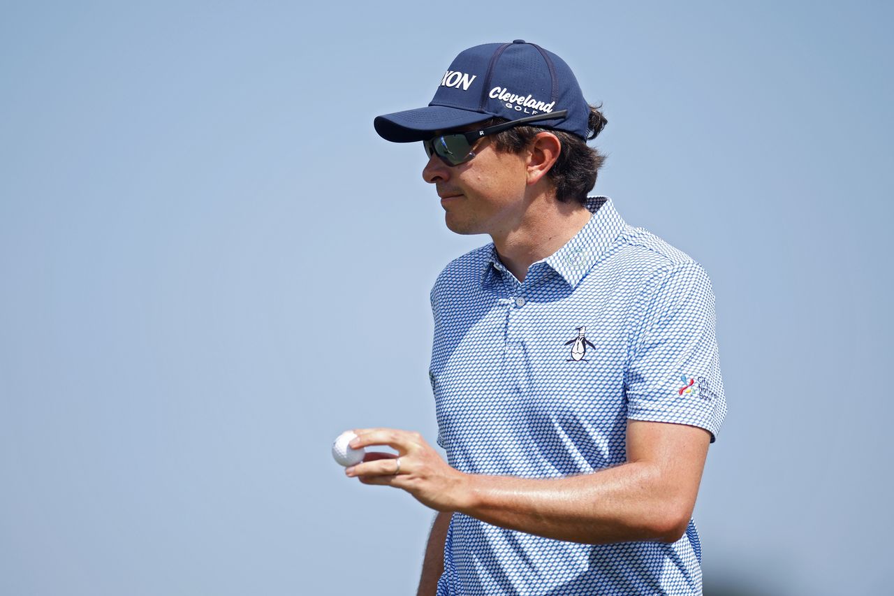 Nico Echavarria waves to the crowd holding a golf ball