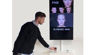 A man in a sweater toggles a joystick around a display showcasing different skin types. 