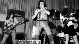 AC DC and Bon SCOTT and Malcolm YOUNG and Angus YOUNG and AC/DC, Malcolm Young (playing Gretsch 6131 Jet Firebird), Bon Scott, Angus Young performing live onstage on first UK tour