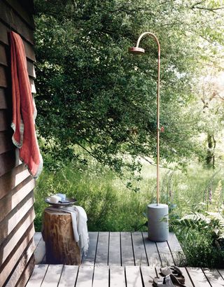 outdoor shower with a grey stone base and brass shower head