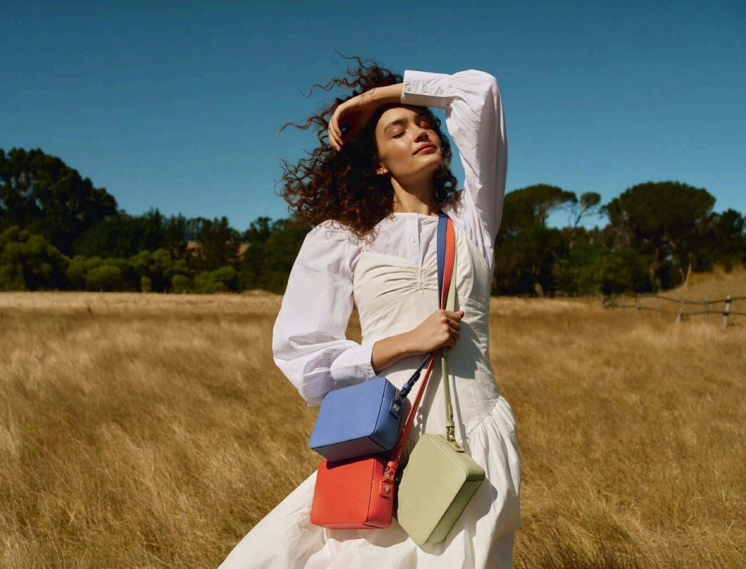 Woman in field wearing 3 bags