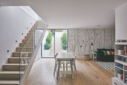 Basement with staircase and clear baluster, wood floor, dining table and feature wall