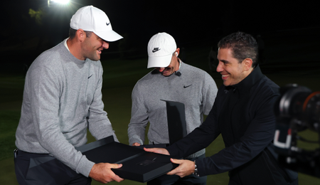 Scottie Scheffler and Rory McIlroy are handed a black box by a man