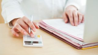 Hands holding a pencil and working with a calculator and notebook