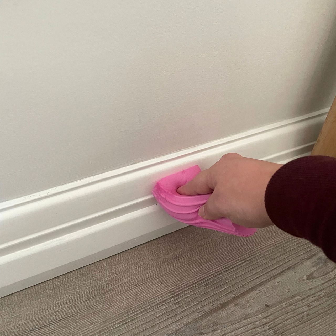 Using a pink damp duster to clean white skirting boards