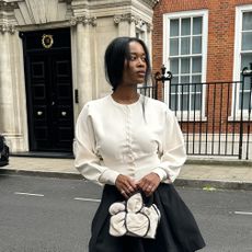 Influencer wearing a white cardigan and black skirt
