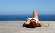 Woman sunbathing on wooden deck - stock photo