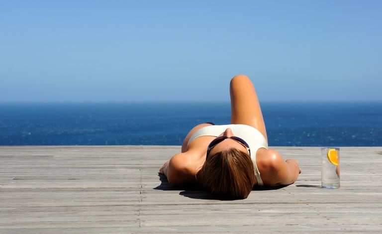 Woman sunbathing on wooden deck - stock photo