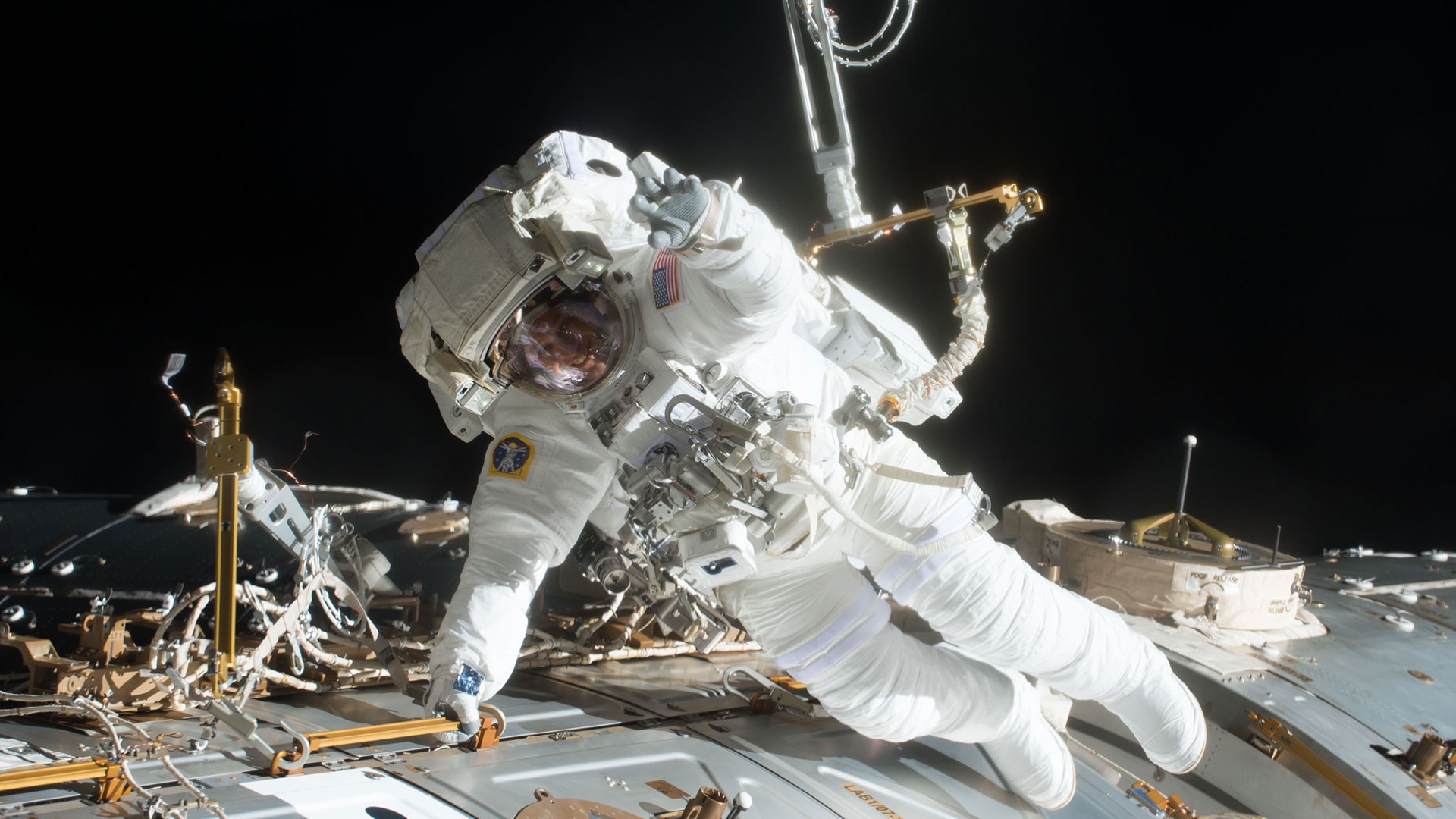 A spacesuited astronaut floats outside of a space station.
