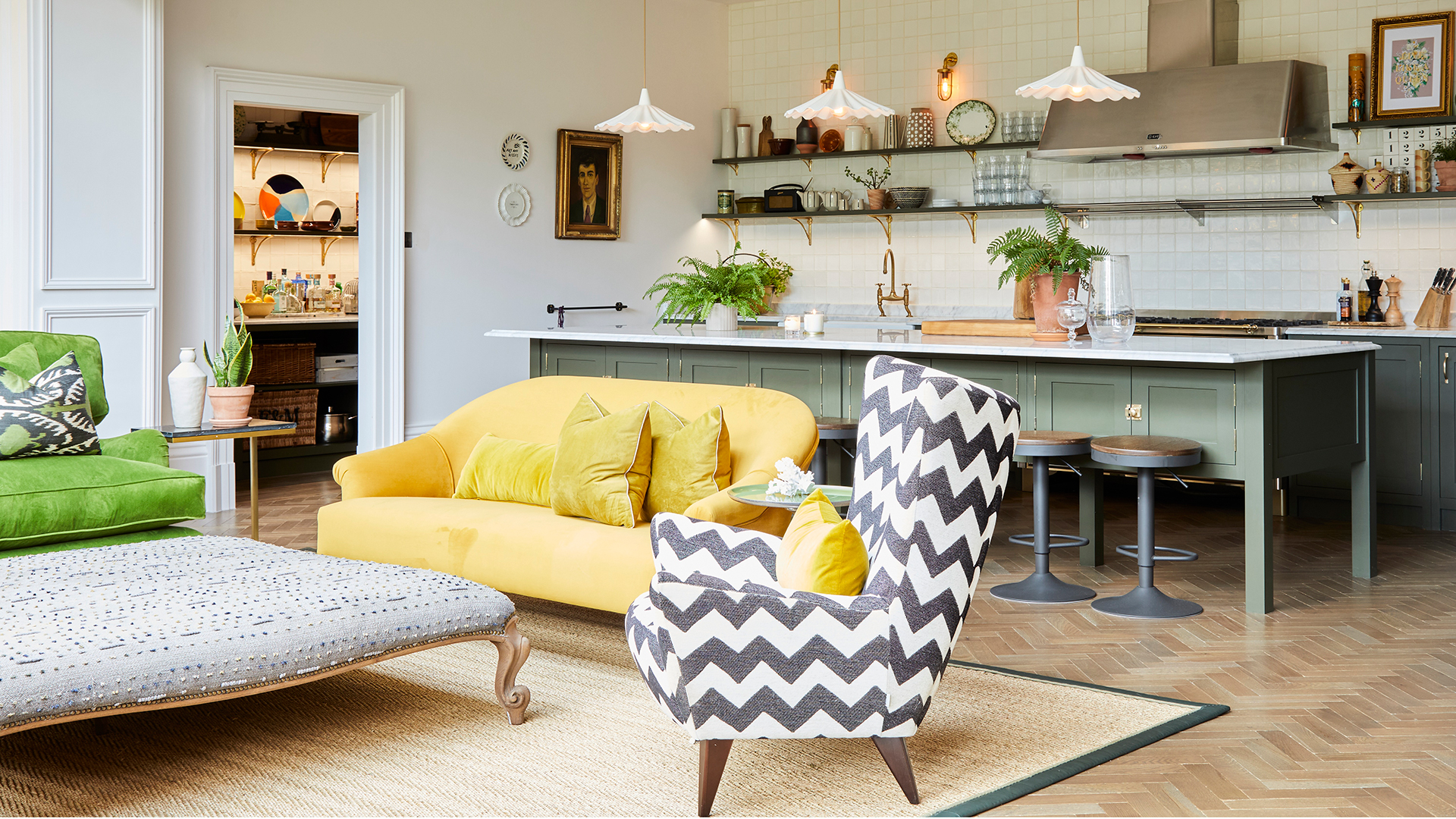Open plan relaxed kitchen and living area with a yellow sofa in front of a light green freestanding kitchen island