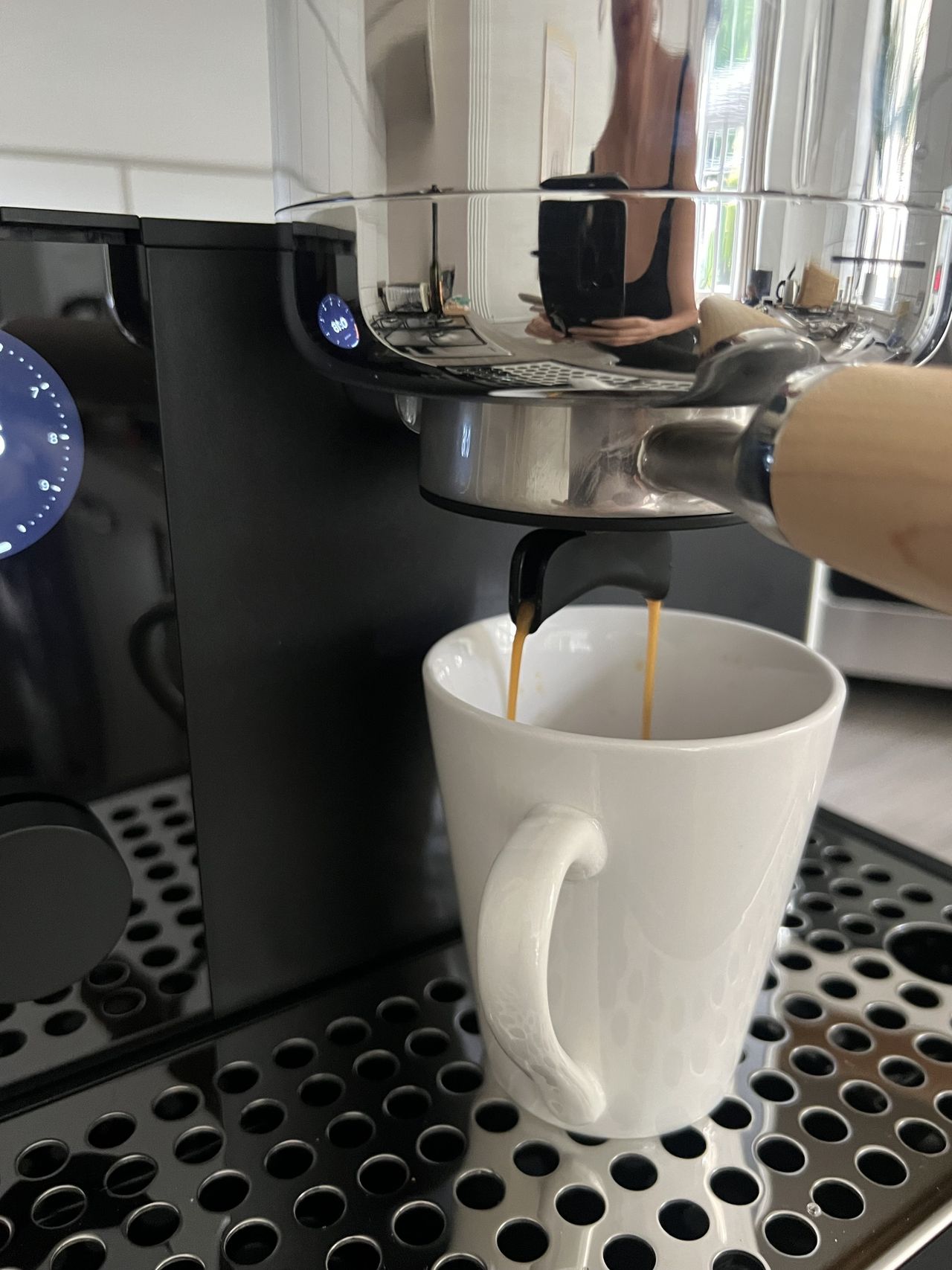 Image of an espresso shot brewing into a white coffee mug from a silver group head.