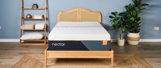 The image shows the Nectar Ultra Hybrid mattress on a wooden bed frame in a blue bedroom
