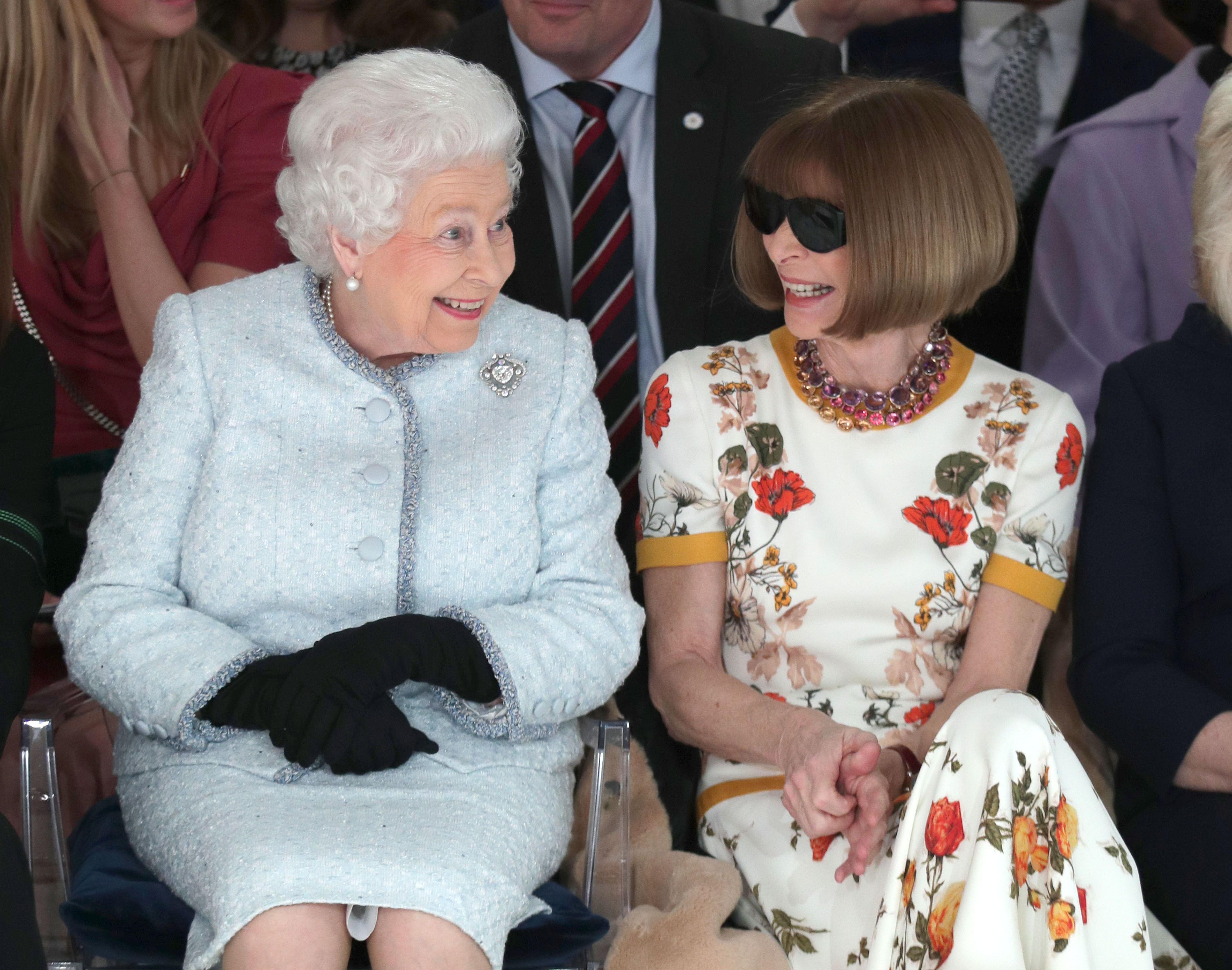 Queen Elizabeth II sits next to Anna Wintour as they view Richard Quinn's runway show before presenting him with the inaugural Queen Elizabeth II Award for British Design as she visits London Fashion Week's BFC Show Space on February 20, 2018 in London, United Kingdom.