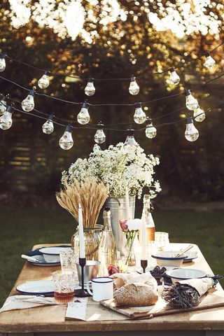 outdoor dining space decorated with festoon lights, candles and flowers